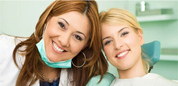 Smiling dentist sitting next to patient